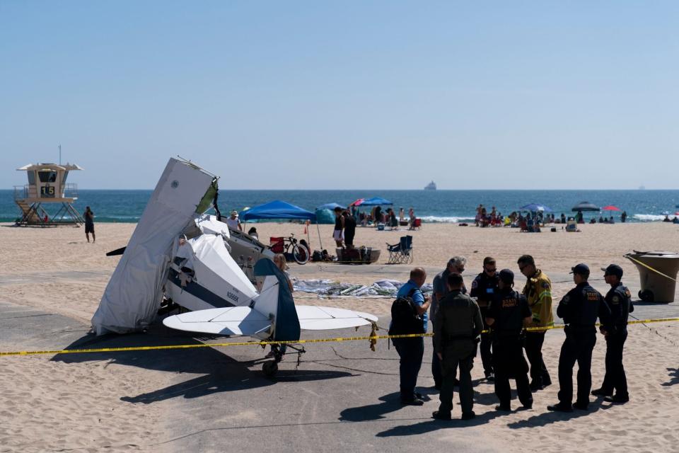 Mandatory Credit: Photo by Jae C Hong/AP/Shutterstock (13044507a) Investigators stand next to a small plane that was pulled from the water after it crashed into the ocean in Huntington Beach, Calif., . The plane towing a banner crashed in the ocean Friday during a lifeguard competition that turned into a real-life rescue along the popular beach Beach Plane Crash, Huntington Beach, United States - 22 Jul 2022