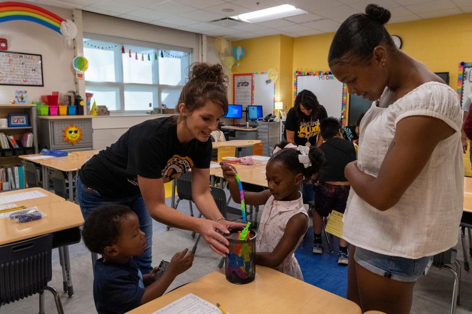 Kindergarten teacher Rachel O’Neal, left, gives new student Milah Lewis, center, a gift during an open house for the new Jefferson Elementary School in Henderson, Ky., Wednesday evening, Aug. 3, 2022. 