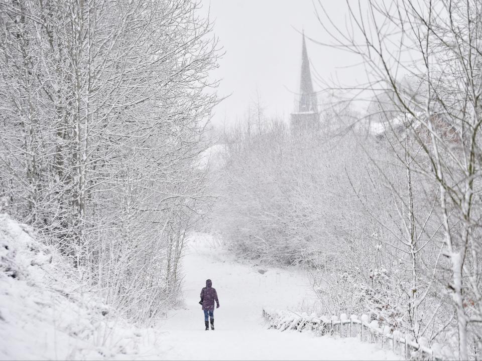 A lady walks in the snow past Silverdale Church on 29 December in Newcastle-Under-Lyme, England (Getty)