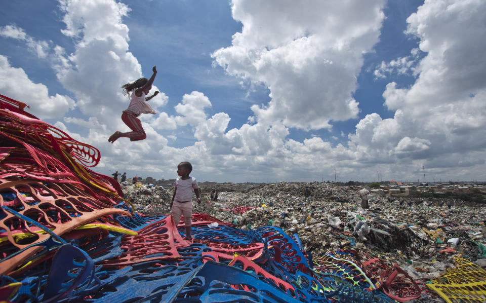 FILE - In this Thursday, Nov. 12, 2015 file photo, Joyce Njeri, 8, enjoys a rare moment of fun playing like a child with Shantel Akinyi, 2, on a pile of discarded sheets of plastic left over from the manufacture of flip-flops, at the garbage dump where Joyce herself and the mother of Shantel both work, in the Dandora slum of Nairobi, Kenya, before a ban on plastic bags came into force in Kenya in 2017. The oil industry in 2020 has asked the United States to pressure Kenya to change its world-leading stance against the plastic waste that litters Africa, according to environmentalists who fear the continent will be used as a dumping ground. (AP Photo/Ben Curtis, File)