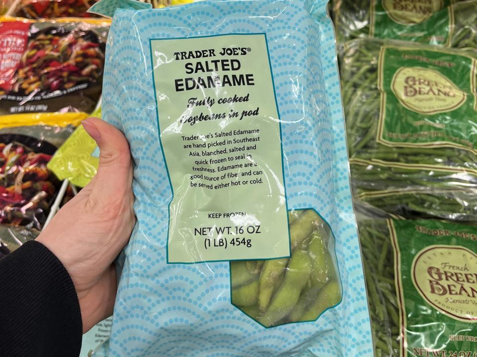 hand holding up a bag of frozen salted edamame at trader joes