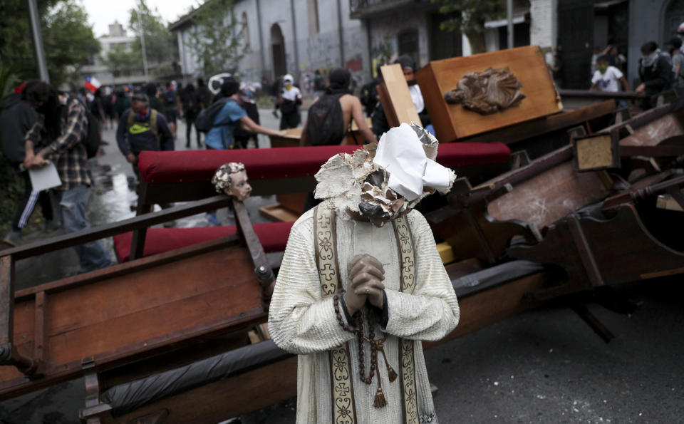 A damaged statue taken from a church forms part of barricade created by antigovernment protesters, in Santiago, Chile, Friday, Nov. 8, 2019. Chile's president on Thursday announced measures to increase security and toughen sanctions for vandalism following three weeks of protests that have left at least 20 dead. (AP Photo/Esteban Felix)