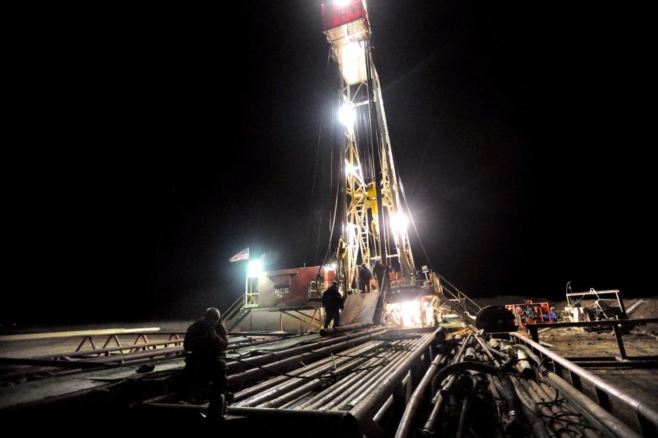 Workers load pipe onto a Jones County oil rig Dec. 27, 2013. 