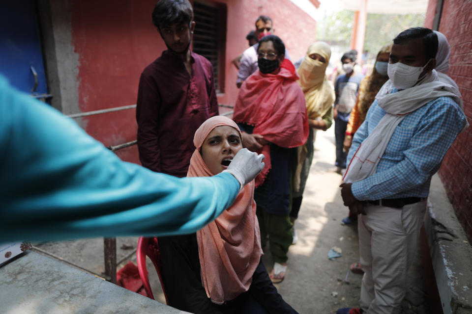 A health worker takes a swab sample to test for COVID-19 in Prayagraj, India, Saturday, April 17, 2021. The global death toll from the coronavirus topped a staggering 3 million people Saturday amid repeated setbacks in the worldwide vaccination campaign and a deepening crisis in places such as Brazil, India and France. (AP Photo/Rajesh Kumar Singh)