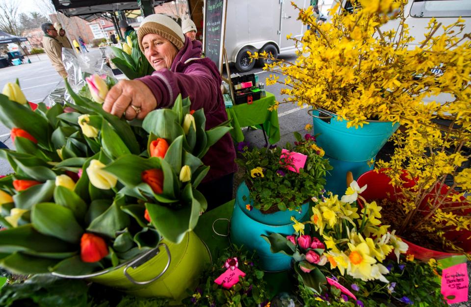Kim Beesley-Shatto pulls a flower for a customer at her Poseys & Pumpkins booth during the opening weekend of the Bloomington Community Farmers' Market on Saturday, April 2, 2022.