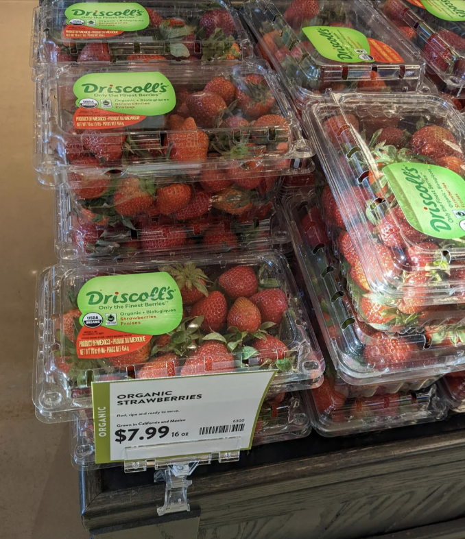 Stacks of organic strawberry packages for sale at $7.99 per 1lb on a store shelf