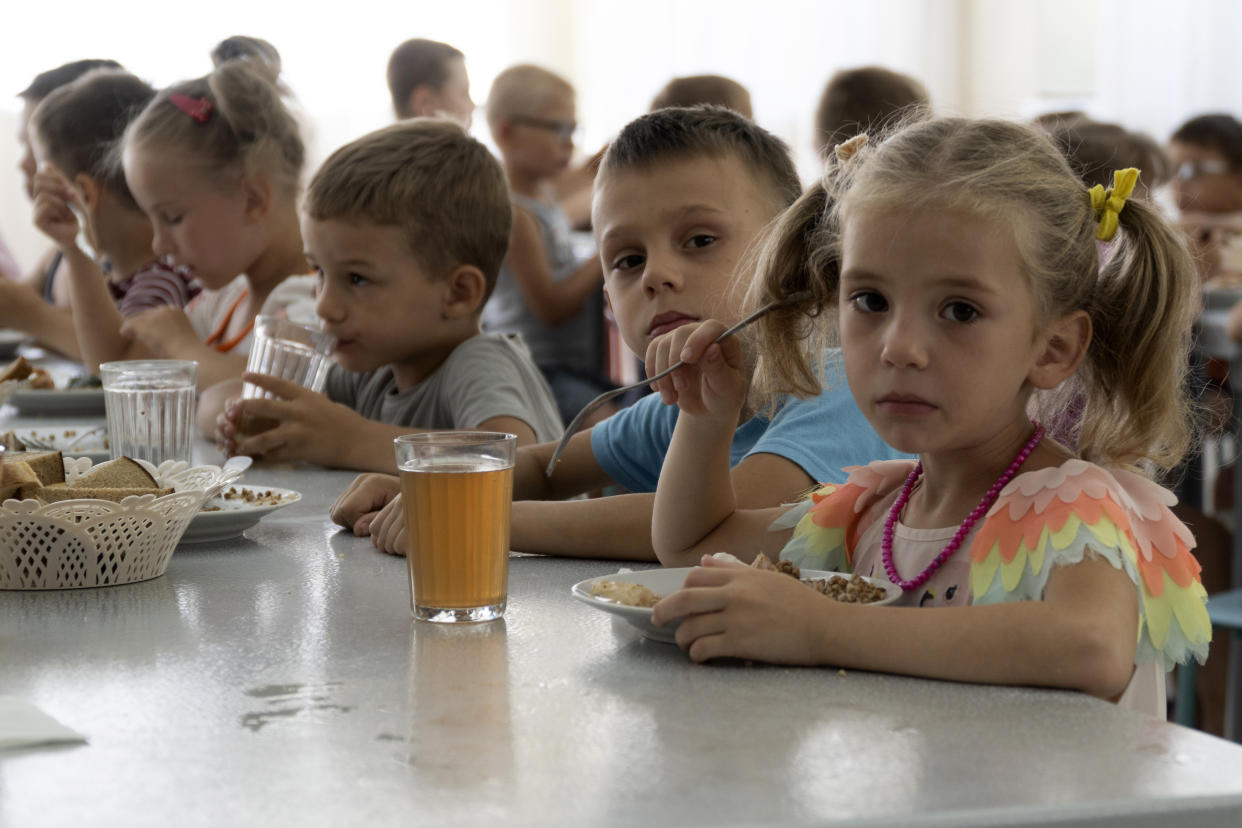 Niños de orfanatos de la región de Donetsk fotografiados durante el almuerzo en un campamento de Zolotaya Kosa, sobre el mar de Azov, el 8 de julio del 2022. Rusia se está apropiando de numerosos niños huéfanos ucranianos y se los está llevando a Rusia, según una investigación de la Associated Press. (AP Photo)