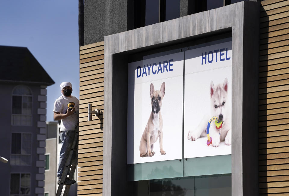 A picture of a French bulldog is featured above the entrance of Dog-E-Den Hollywood near an area on North Sierra Bonita Ave. where Lady Gaga's dog walker was shot and two of her French bulldogs stolen, Thursday, Feb. 25, 2021, in Los Angeles. The dog walker was shot once Wednesday night and is expected to survive his injuries. The man was walking three of Lady Gaga's dogs at the time but one escaped. (AP Photo/Chris Pizzello)