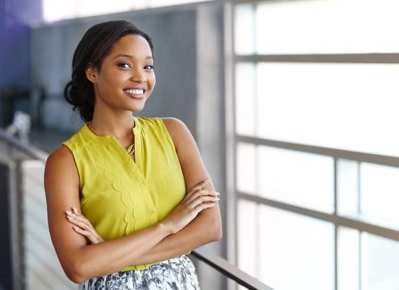 Smiling professionally dressed woman with arms crossed.