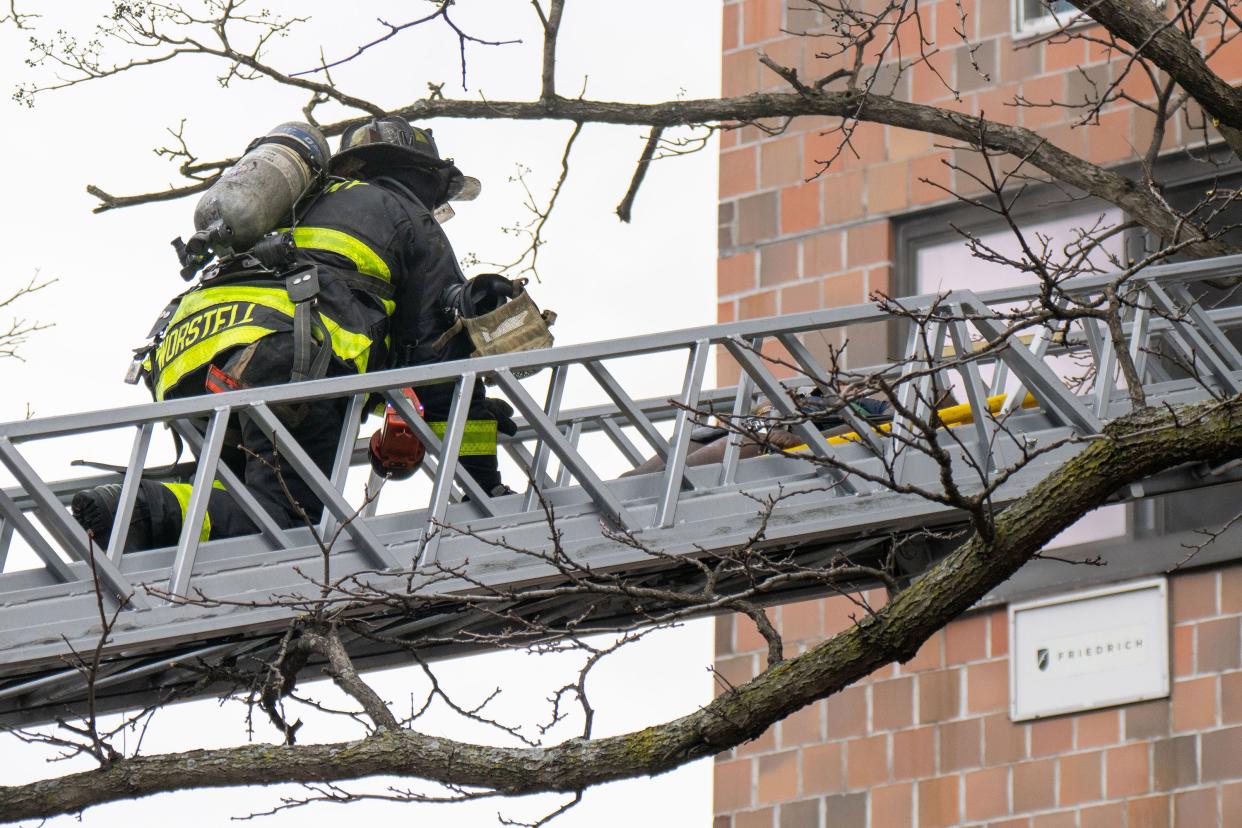 An injured person is brought down on a ladder after firefighters rescued them from an apartment blaze on Sunday, Jan. 9, 2022.
