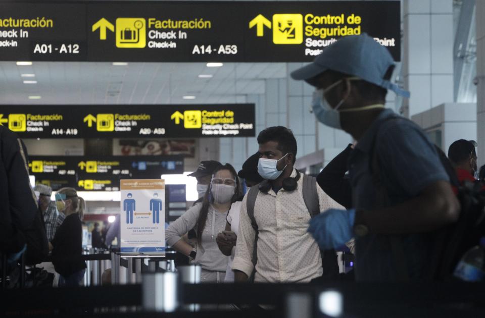 Passengers stand in the check-in area of Tocumen International Airport for a departing flight in Panama City, Monday, Oct. 12, 2020. Panama is lifting a broad spectrum of COVID-19 pandemic-related restrictions on Monday, including re-opening international flights and allowing hotels, casinos, and tourism-related activities. (AP Photo/Arnulfo Franco)