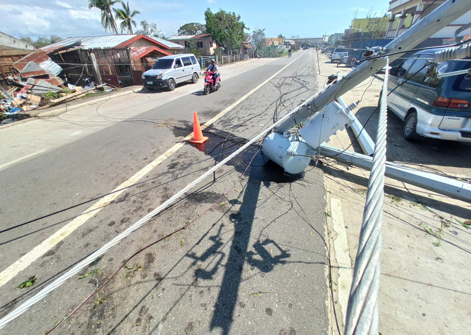 A man rides his motorcycle past an electrical post that was damaged by Typhoon Phanfone in Balasan Town, Iloilo province, central Philippines on Thursday Dec. 26, 2019. A strong typhoon that barreled through the central Philippines left at least 20 people dead and forced thousands to flee their homes, devastating Christmas celebrations in the predominantly Catholic country. (AP Photo/Leo Solinap)