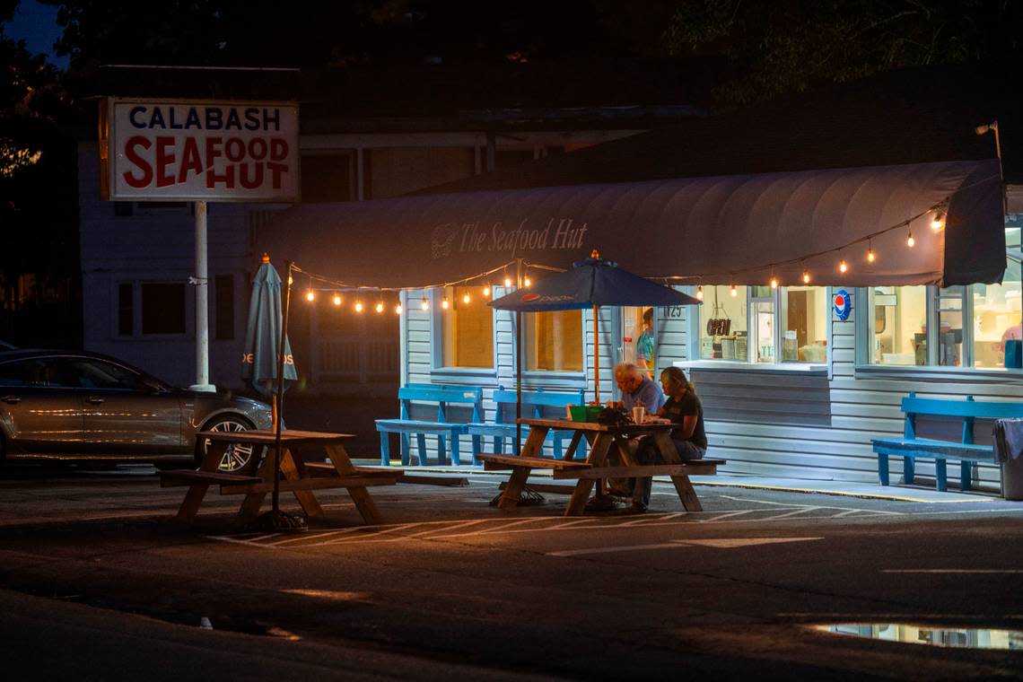 Just after 9 p.m. the last customers at the Seafood Hut dine beneath the lights at one of the many outdoor tables on Thursday, June 27, 2024 in Calabash, N.C.