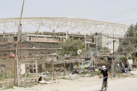 A boy rides his bicycle past a stadium being built by a Turkish company in Baghdad's Habibiya district September 2, 2015. REUTERS/Ahmed Saad