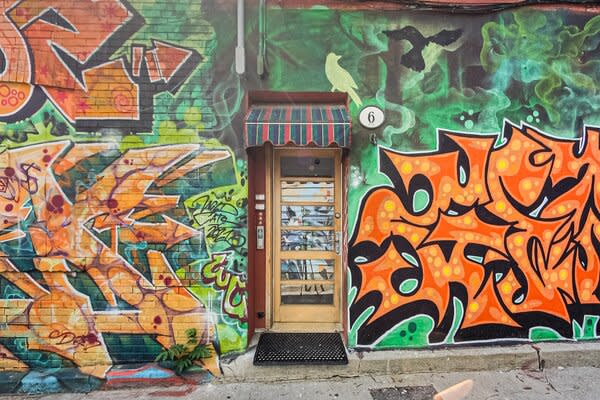 The building's entrance sits along a popular alleyway, enveloped with vibrant graffiti.