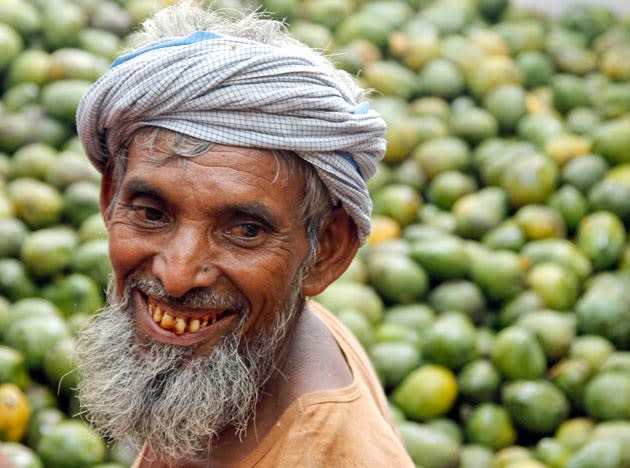 A worker smiles as he sorts mangoes at a wholesale market on the outskirts of Allahabad, India, Saturday, July 30, 2011. (AP Photo/Rajesh Kumar Singh)