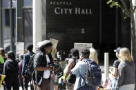 Protesters block a street in front of Seattle City Hall, Monday, July 13, 2020, following a news conference where Police Chief Carmen Best and Mayor Jenny Durkan spoke critically about a plan backed by several city council members that seeks to cut the police department's budget by 50 percent. (AP Photo/Ted S. Warren)