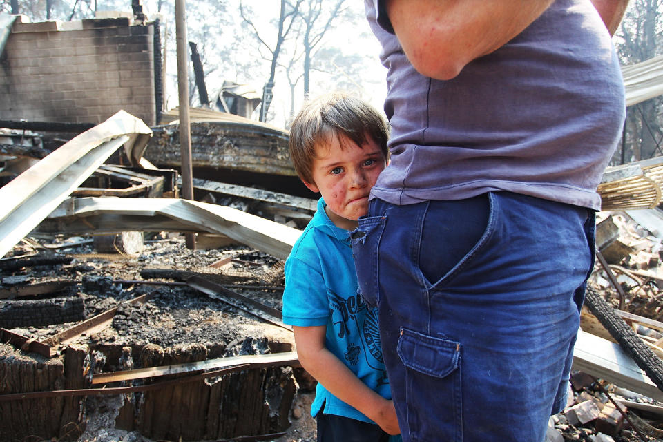 Lyndon Dunlop stands by his father as they inspect the damage to his grandparent's home of 41 years destroyed by bushfire on October 21, 2013 in Winmalee, Australia. (Photo by Lisa Maree Williams/Getty Images)