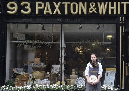 Affineur and cellar manager Dan Bliss holds a wheel of 'Stinking Bishop' cheese, which has a royal warrant from the Prince of Wales outside of Paxton and Whitfield in central London, Britain, August 21, 2015. Paxton & Whitfield, Britain's oldest cheesemonger, has two royal warrants for Queen Elizabeth and the Prince of Wales. Every year Queen Elizabeth grants about 20 royal warrants, the gold emblem of the British monarchy, in a practice dating back to medieval times. REUTERS/Toby Melville