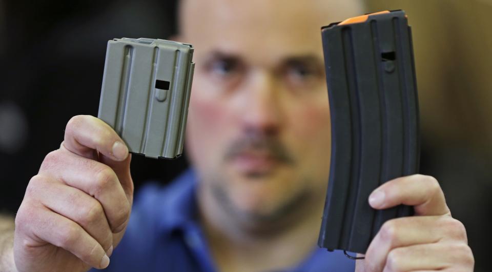 In this April 10, 2013 file photo, Jonathan Scalise, owner of Ammunition Storage Components, holds up a 10-round, left, and a 30-round magazine that his company manufacturers for the AR-15 rifle in New Britain, Conn. Gun rights supporters are suing Connecticut officials over part of a 2013 state gun control law passed after the Sandy Hook school shooting, saying it unconstitutionally bans people from loading more than 10 rounds of ammunition into their firearms. The lawsuit filed in U.S. District Court on Tuesday, March 10, 2020 cites the Second Amendment right to bear arms and the ability of people to better defend themselves with more bullets in their guns. (AP Photo/Charles Krupa, File)