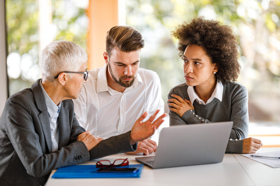 different generations of coworkers looking at a computer and talking