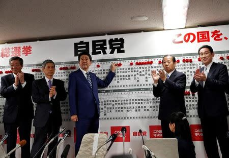 Japan's Prime Minister Shinzo Abe, leader of the Liberal Democratic Party (LDP), puts a rosette on the name of a candidate who is expected to win the lower house election, as his party's lawmakers applaud at the LDP headquarters in Tokyo, Japan October 22, 2017. REUTERS/Kim Kyung-Hoon