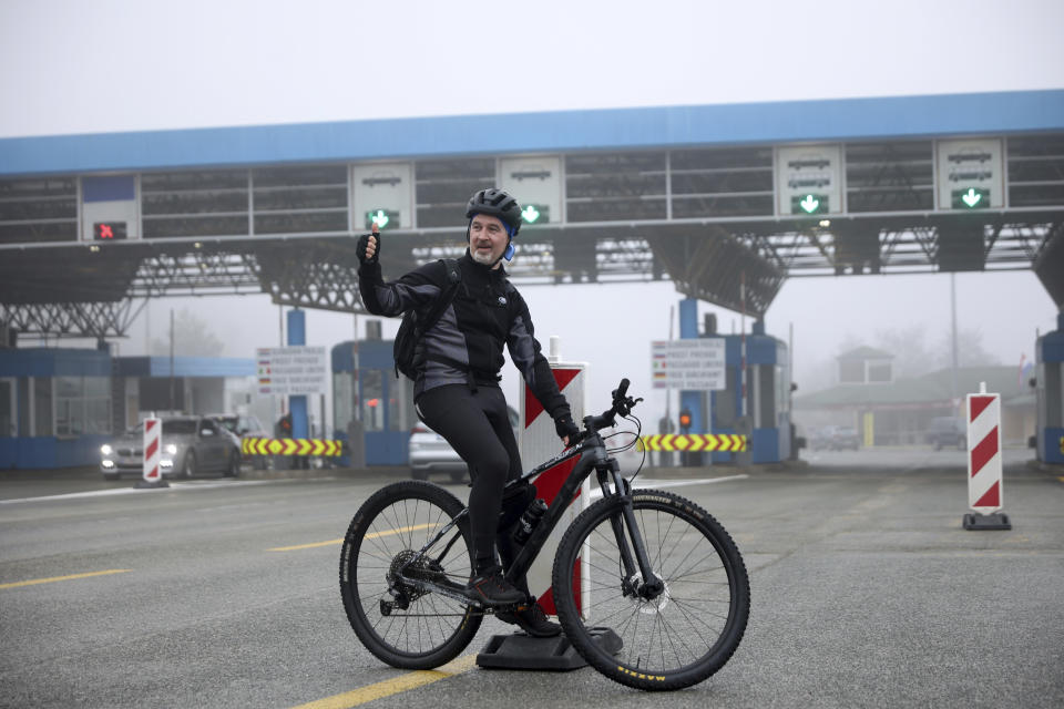 Cyclist Goran Loncar poses for a photo after crossing the Rupa border between Croatia and Slovenia for the first time without any interruptions, Croatia, Sunday, Jan. 1, 2023. At the stroke of midnight on Saturday, Croatia switched to the shared European currency, the euro, and removed dozens of border checkpoints to join the world's largest passport-free travel area, completing a dream conceived 30 years ago when it fought a war for independence from Yugoslavia in which 20,000 people were killed and hundreds of thousands displaced. (AP Photo/Armin Durgut)