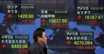 A pedestrian walks past an electronic board displaying various countries' share prices outside a brokerage in Tokyo December 19, 2013. REUTERS/Yuya Shino