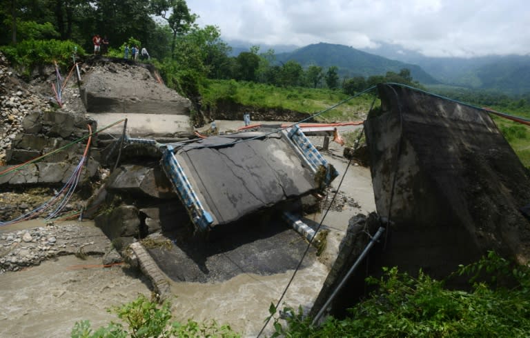 Bystanders look at a damaged bridge after landslides in the village of Garidhura, some 35kms from Siliguri in the eastern Indian state of West Bengal, on July 1, 2015