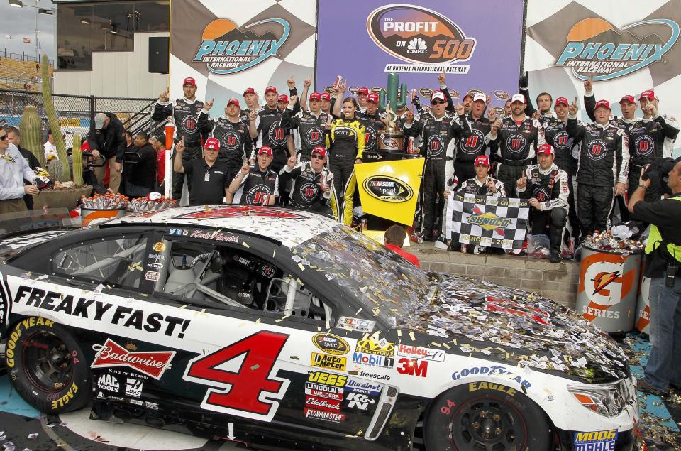 Kevin Harvick, standing to the right of the winner's trophy, joins his crew in posing for photographers in Victory Lane after winning the NASCAR Sprint Cup Series auto race Sunday, March 2, 2014, in Avondale, Ariz. (AP Photo/Ross D. Franklin)