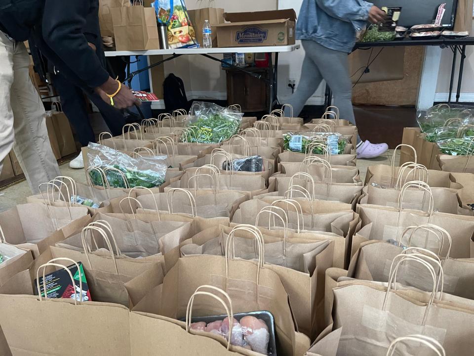 Members of PLP Rochester add items, including fresh produce, chicken and canned goods, to double-bagged and stamped paper bags for their free, bi-weekly Grocery Program. This weekend, they served over 80 families.