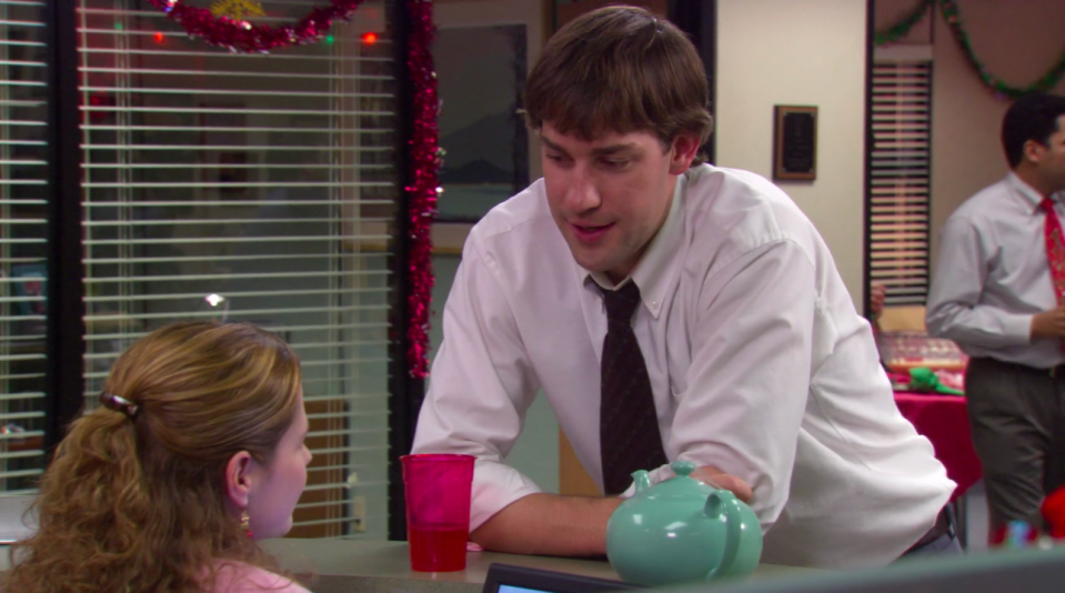 Jim leaning over Pam's desk with the turquoise teapot