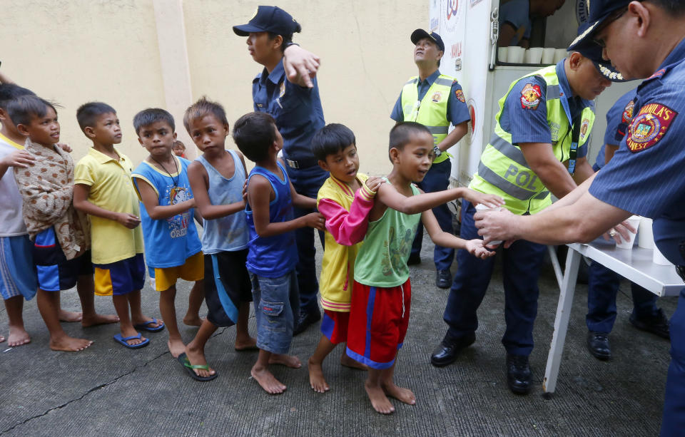 Manila police distribute rice porridge to residents living along the coastal community of Baseco as they evacuate during the onslaught of Typhoon Mangkhut which barreled into northeastern Philippines before dawn Saturday, Sept. 15, 2018 in Manila, Philippines. Philippine officials were assessing damage and checking on possible casualties as Typhoon Mangkhut on Saturday pummeled the northern breadbasket with ferocious wind and rain that set off landslides, damaged an airport terminal and ripped off tin roofs. (AP Photo/Bullit Marquez)