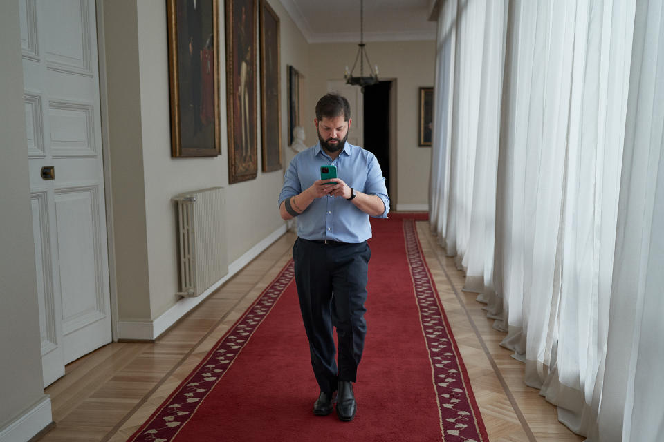 Boric checks his phone in the corridor of La Moneda presidential palace on Aug. 12.<span class="copyright">Luján Agusti for TIME</span>