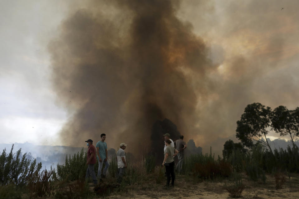 Local residents watch a forest fire move up a slope towards the village of Casal da Quinta, outside Leiria, central Portugal, Tuesday, July 12, 2022. Hundreds of firefighters in Portugal continue to battle fires in the center of the country that forced the evacuation of dozens of people from their homes mostly in villages around Santarem, Leiria and Pombal. (AP Photo/Joao Henriques)