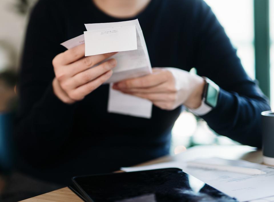 Woman planning budget and calculating expenses with digital tablet while going through various receipts