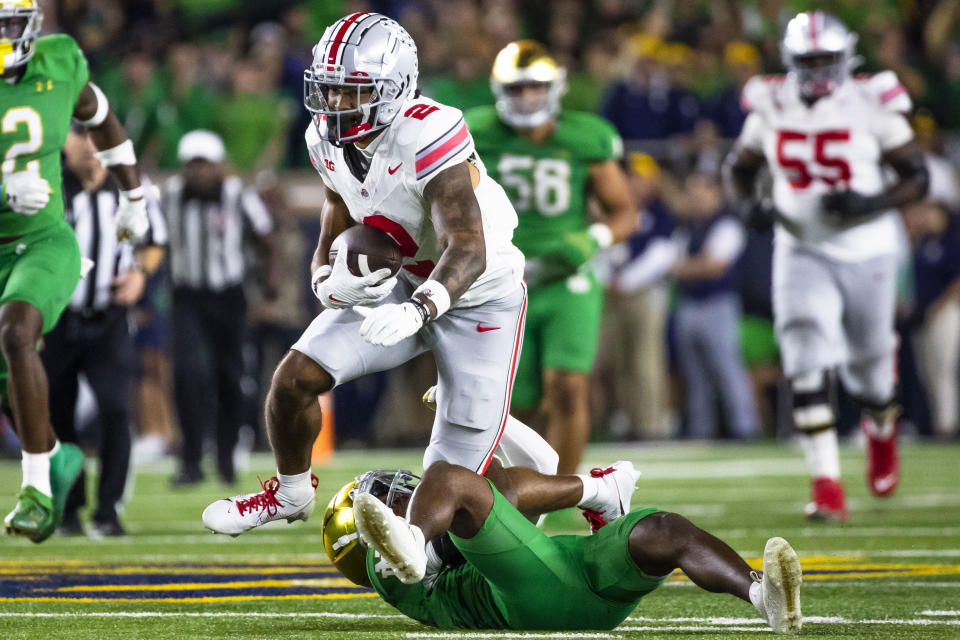 Ohio State running back Emeka Egbuka (2) gets tripped by Notre Dame safety Thomas Harper during the second half of an NCAA college football game Saturday, Sept. 23, 2023, in South Bend, Ind. (AP Photo/Michael Caterina)