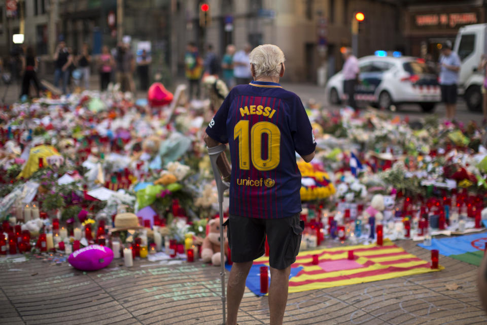 A man stands next to flags, flowers, messages and candles in tribute to the victims of the Barcelona terror attack. (AP Photo/Emilio Morenatti)