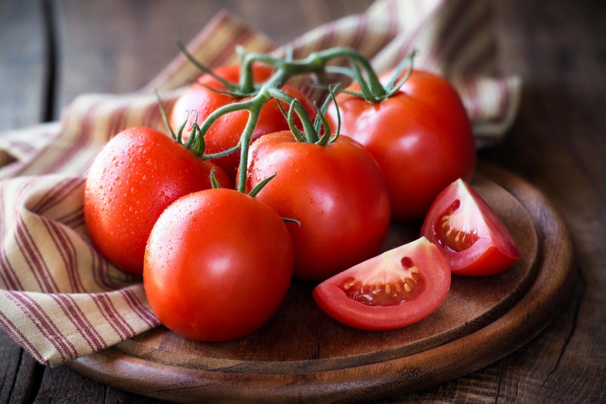 Fresh red ripe tomatoes on the vine on a dark rustic cutting board