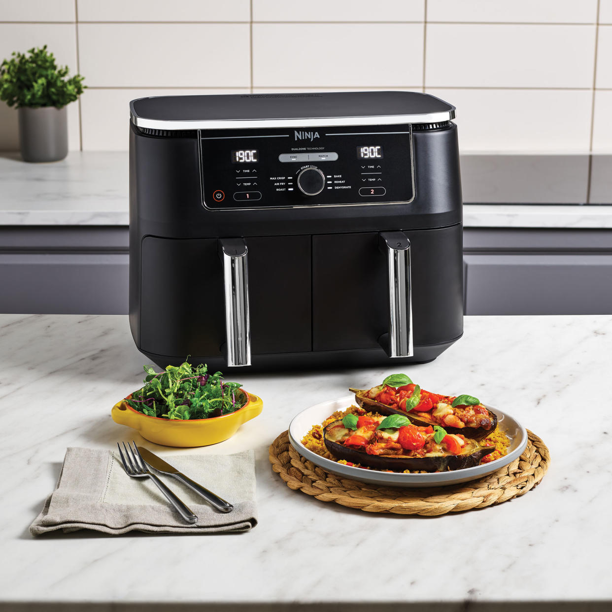  Black air fryer in kitchen with food on kitchen island. 