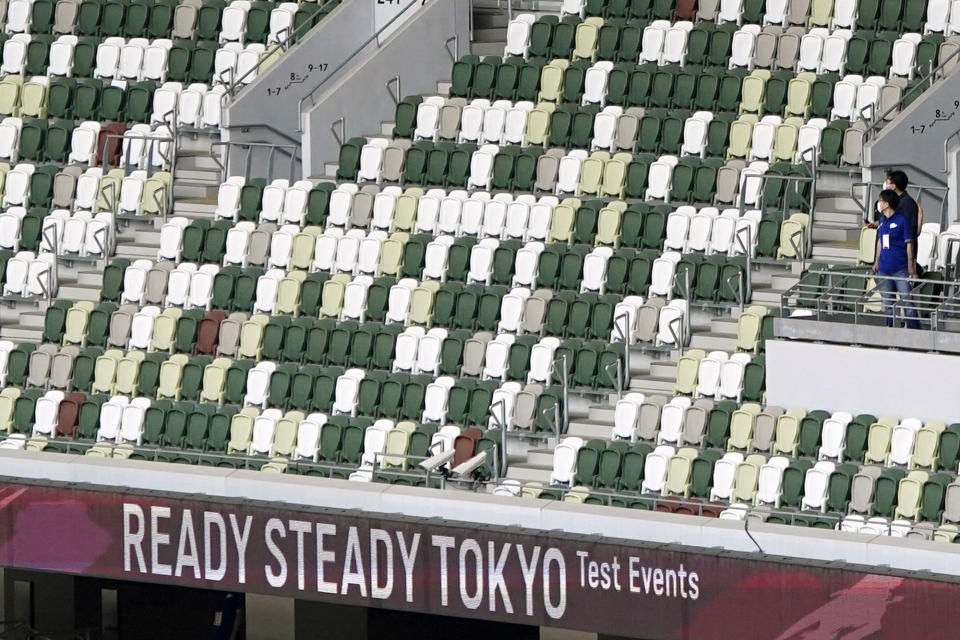 A staff wearing face mask are seen with empty spectators' seats during an athletics test event for Tokyo 2020 Olympics Games at the National Stadium, in Tokyo, Japan, Sunday, May 9, 2021. Fans will be banned from Tokyo-area stadiums and arenas when the Olympics begin in two weeks, the city’s governor said Thursday, July 8, 2021, after meeting with organizers of the pandemic-postponed games.(AP Photo/Shuji Kajiyama)