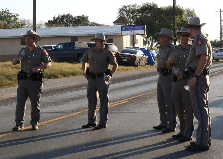 Police block a road in Sutherland Springs, Texas, after a mass shooting at the First Baptist Church (rear)