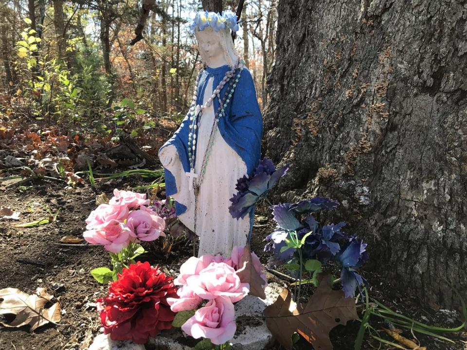 A small statue of the Virgin Mary, surrounded by flowers, is located just off Highland View Road.