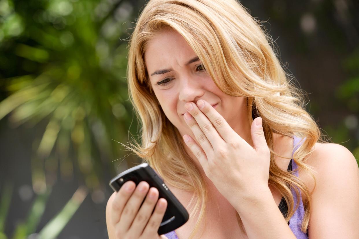 A distressed woman looking at her phone.