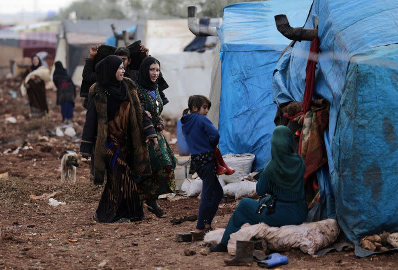 Internally displaced people stand outside tents at a makeshift camp in Azaz