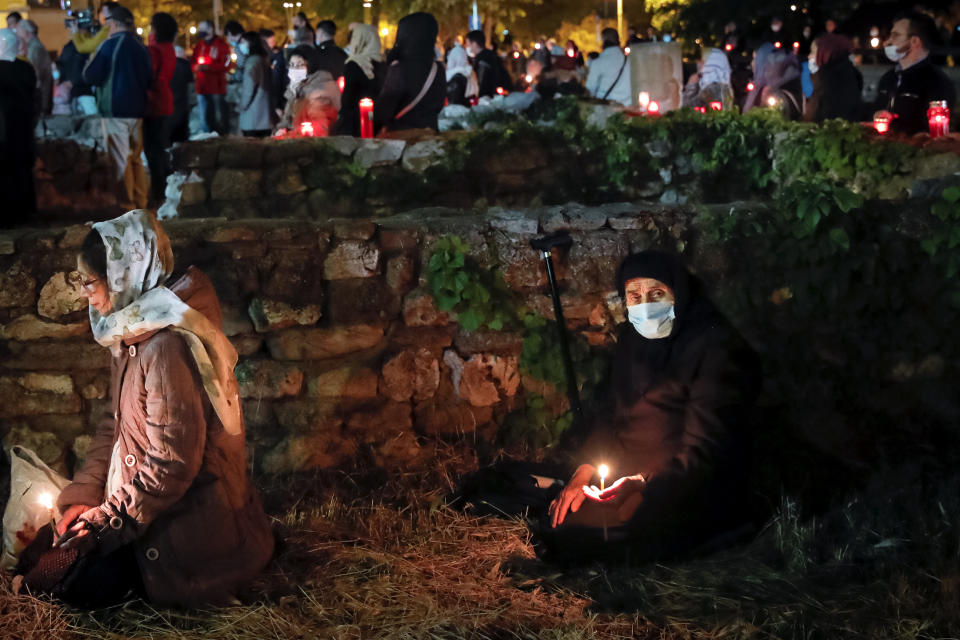 Orthodox worshipers, a few wearing masks for protection against the COVID-19 virus, are spread around an open archaeological site outside the Cathedral of Saints Peter and Paul, which includes ruins dating as far back as the Roman Empire, during a religious service in the Black Sea port of Constanta, Romania, Wednesday, May 27, 2020. (AP Photo/Vadim Ghirda)