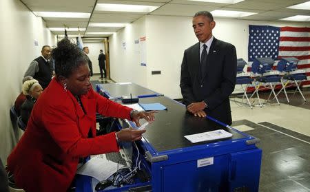 U.S. President Barack Obama gets his ballot as he takes part in early voting at a polling station in Chicago, Illinois October 20, 2014. REUTERS/Kevin Lamarque