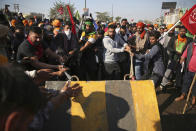 Protesting farmers remove a concrete barricade set up by policemen, as they attempt to move towards Delhi, at the border between Delhi and Haryana state, Friday, Nov. 27, 2020. Thousands of agitating farmers in India faced tear gas and baton charge from police on Friday after they resumed their march to the capital against new farming laws that they fear will give more power to corporations and reduce their earnings. While trying to march towards New Delhi, the farmers, using their tractors, cleared concrete blockades, walls of shipping containers and horizontally parked trucks after police had set them up as barricades and dug trenches on highways to block roads leading to the capital. (AP Photo/Altaf Qadri)