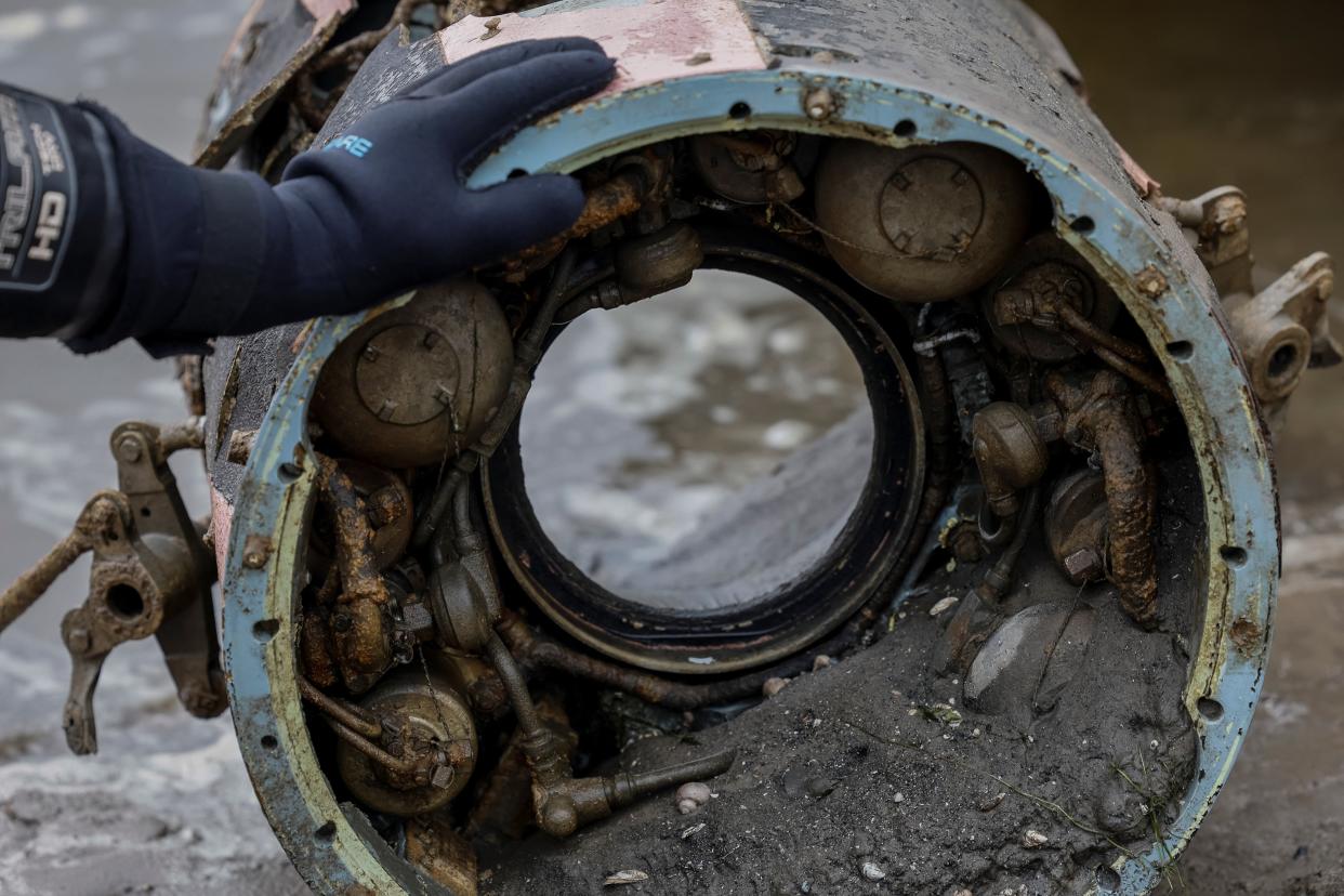 A deminer touches the wreckage of a retrieved S-300 rocket, which fell a few months ago in the Dnipro river and became visible after water level sharply dropped following the Kakhovka dam destruction, amid Russia's attack on Ukraine, in Zaporizhzhia, Ukraine, June 12, 2023. (REUTERS)