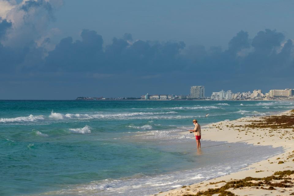 A tourist fishes from the shore in Cancun, Mexico, Thursday, June 11, 2020. (AP Photo/Victor Ruiz)